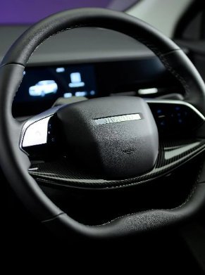 Close-up of a car steering wheel with a digital display in the background.
