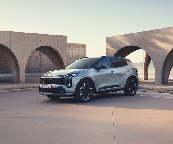Silver SUV parked on concrete surface with arched stone structures behind.